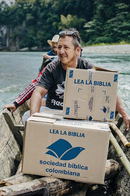Homem em canoa com caixas de Bíblias